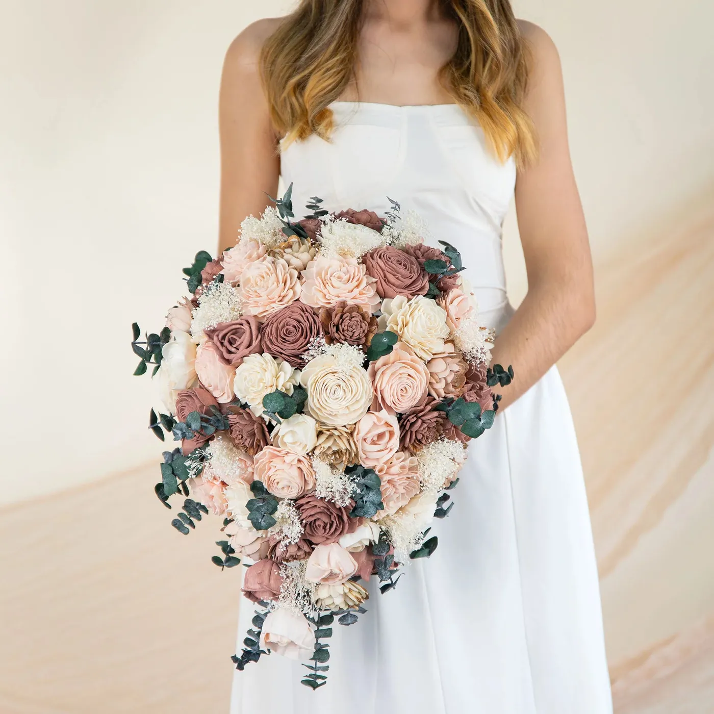 Bride holding The Best cascade bouquet in blush, dusty rose and cream