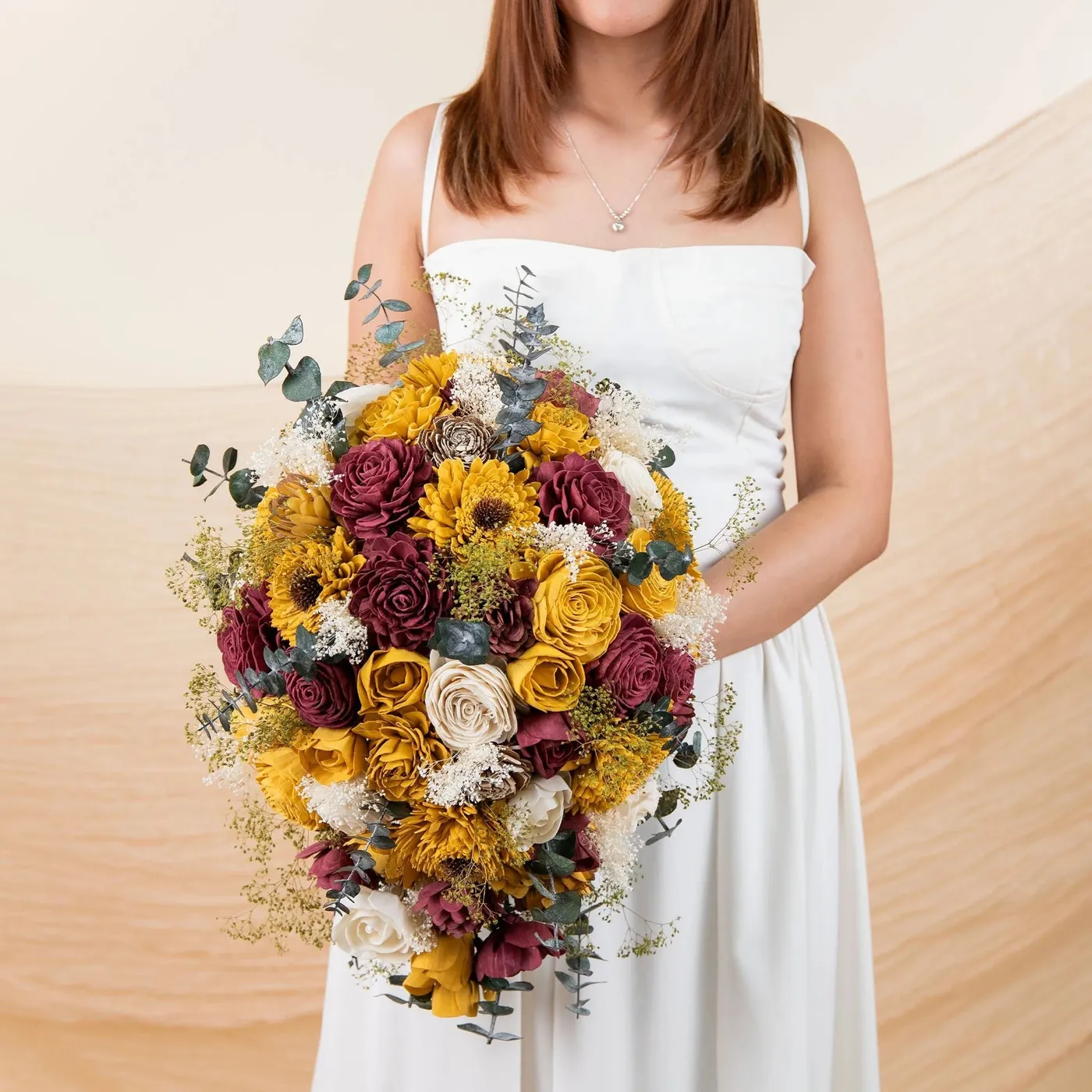 Bride holding the Sunflower Daze bouquet of wood sunflowers and burgundy blooms