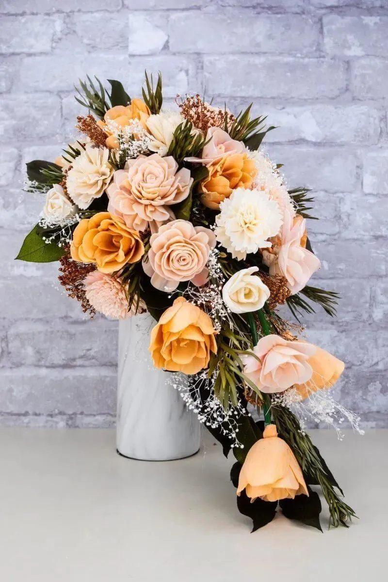 Custom cascade bouquet in peach and cream standing in a white vase