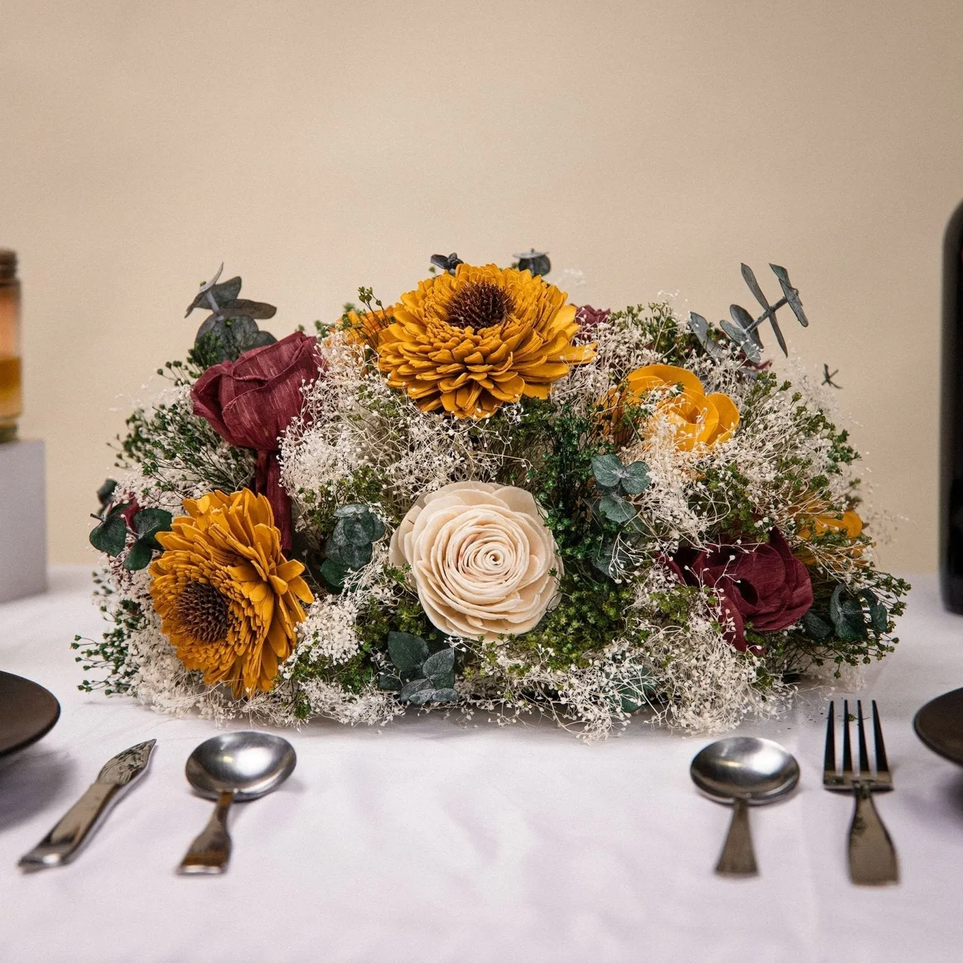 Wild style centerpiece of wood sunflowers and burgundy blooms on a set reception table
